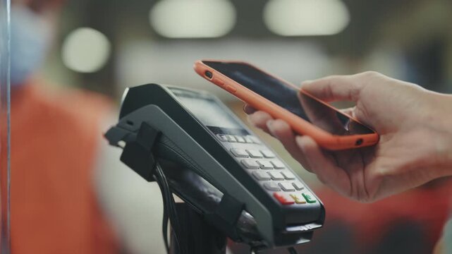Fast contactless shopping transaction, Modern store checkout with contactless phone payment and masked worker