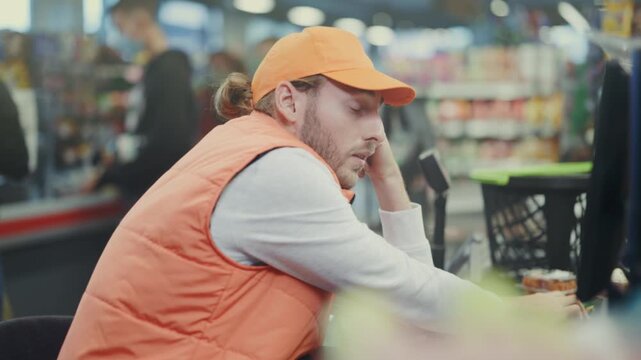 Tired cashier reviewing receipts, Disinterested employee in casual clothing examining sales documents calmly