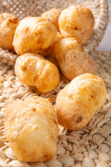 Fototapeta premium Cheese bread, a delicious Brazilian cheese bread, in a basket on a rustic woven straw surface, selective focus.
