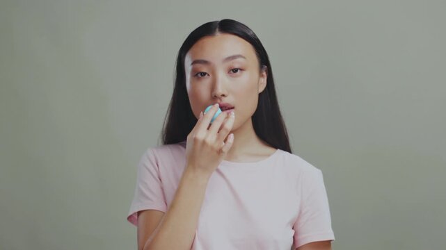 Closeup portrait of beauty influencer applying hydrating lip balm with subtle smile and soft lighting