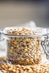 Uncooked green lentil in jar on white table.