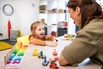 Speech therapist assisting a young girl with speech articulation and therapy exercises, encouraging...