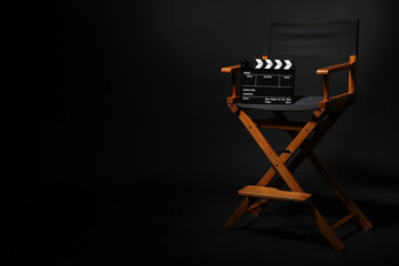 Film director's chair with clapperboard on black background, space for text