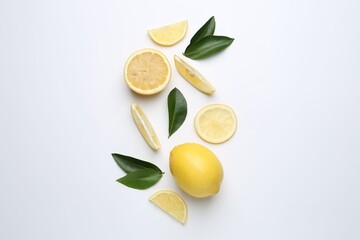 Fresh yellow lemons and green leaves on white background, flat lay