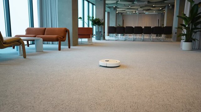 Robotic vacuum cleaner cleaning carpet in modern office