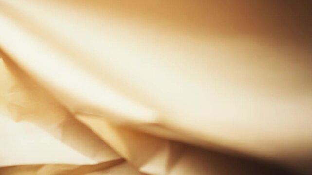 Crumpled paper creating an abstract texture background, featuring folds and creases with warm sepia tones, and natural light casting subtle shadows and bright highlights across the surface