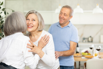 Fototapeta premium As two elderly woman meet, they exchange warm greeting by embracing with a gentle kiss on the cheek