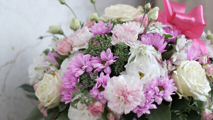 Vibrant bouquet of pink and white flowers featuring roses and carnations with a bright pink satin bow