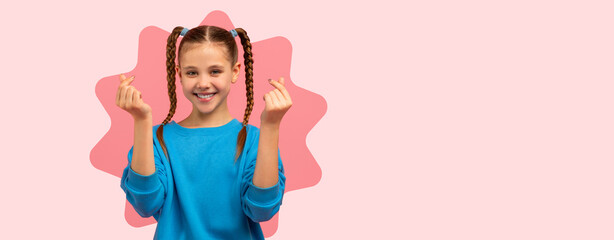 A young girl smiles and makes hand gestures while wearing a blue shirt. Her hair is styled in...