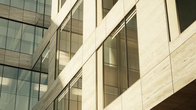 Modern architectural details defining a commercial building exterior with transparent glass windows reflecting light and intricate patterns, contrasting with textured limestone panels on a sunny day