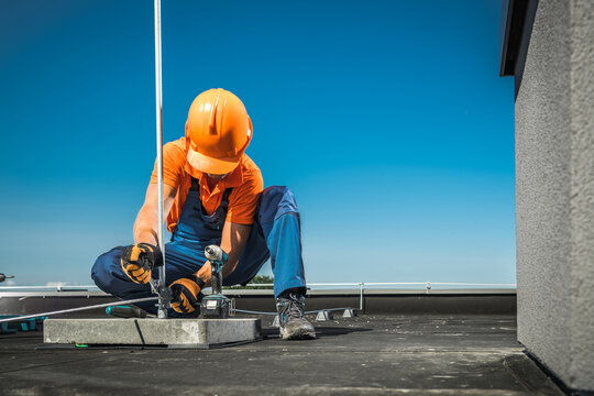 Worker Installs Lightning Protection Equipment on Rooftop in Bright Weather