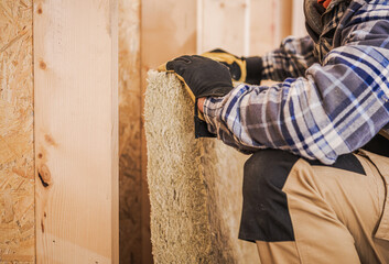 Worker Installs Insulation in Wooden Frame Structure