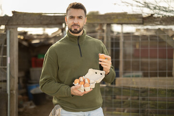 Man holding fresh eggs in a chicken coop © JackF
