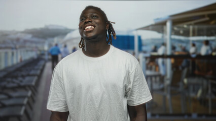 Fototapeta premium Man smiling with face tilted back on cruise deck near ship rail, wearing white t shirt and dreadlocks, outdoors and relaxed; joy relaxation travel.