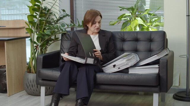 HR manager reviewing candidate files on office sofa
