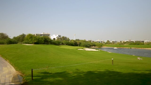 Golf course landscape with lush green grass, sand traps, and water features in sunny weather