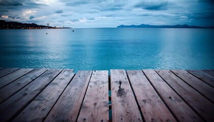 Fototapeta premium Wooden pier extending into calm turquoise sea at sunset under cloudy sky