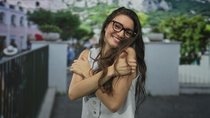 Fototapeta premium Woman wearing glasses crosses arms across chest on a bustling city street during daytime in soft afternoon sunlight; denial.
