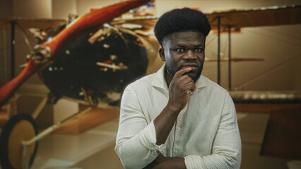 Man hand on chin in museum building beside vintage airplane propeller, looking pensive and studying the display  thoughtful. © Krakenimages.com