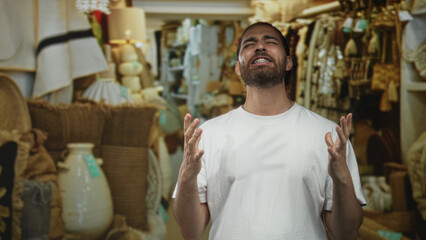 Man with hands raised and mouth open showing braces in a retail shop building, white t shirt and...