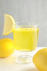 Yummy yellow jelly in dessert bowl and lemons on white table, closeup