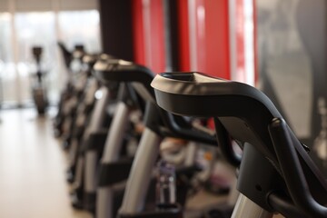 Many stationary bicycles in gym, closeup. Space for text