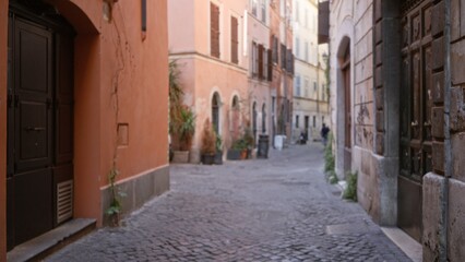 Obraz premium Blurred narrow cobblestone roman street scene with shallow bokeh and soft defocused buildings street; backdrop copyspace backplate calm.
