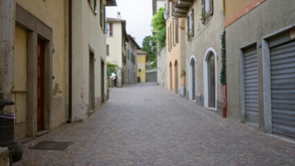 Fototapeta premium Narrow cobblestone scene with soft bokeh and defocused building facades and muted colors, street; background backdrop copyspace calm.