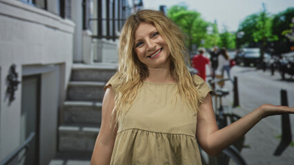 Fototapeta premium Woman with palm up gesture on a city street smiling and presenting her hand; cheerful confident optimism.