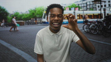 Fototapeta premium Young african american man wearing white polo makes roaring gesture with hand on busy city street; urban adventure joy.