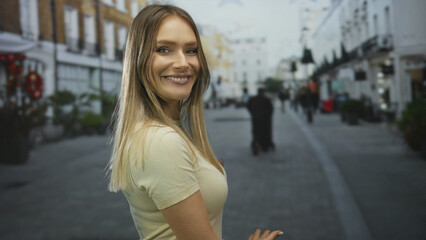 Fototapeta premium Woman smiling with arms outstretched in a bustling city street showing lively urban atmosphere with buildings and people in the background.