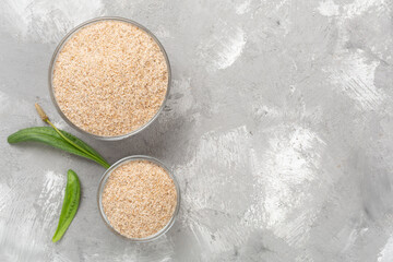 Psyllium husk powder with fresh leaves on concrete background, top view © Liami