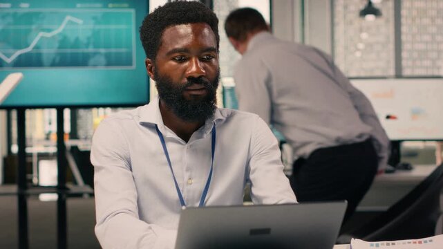 Black man worker, monetary data, performance review, laptop screen, corporate workspace, analytics dashboard, resource allocation, productivity, global business success. Business intel.