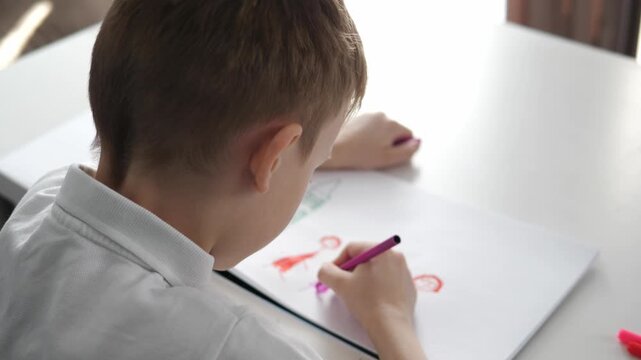 Little child drawing with colorful markers at a table. Creative learning activity at home. Concept of childhood development, education, imagination and fine motor skills.