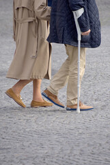 Senior couple walking with cane outdoors.
