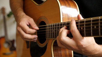 Musician playing acoustic guitar with focus on hands and strings. Man practicing musical instrument chords