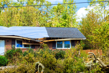 Storm damage shows fallen trees roof repairs on house in suburban area © ungvar