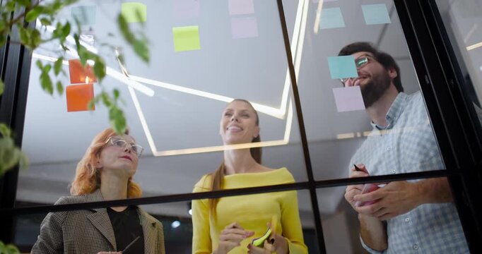 Team members collaborate using sticky notes in a modern office space to brainstorm ideas and solve problems during a workshop session in the afternoon