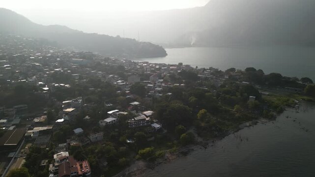 Aerial of San Pedro La Laguna town on Lake Atitlan with hazy sunset in Guatemala