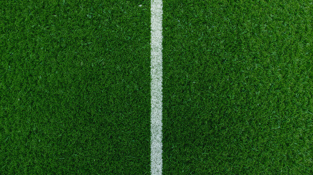 Top down view of a soccer field featuring a detailed grass texture and a bold white sideline. The image showcases close up green turf with visible blades.
