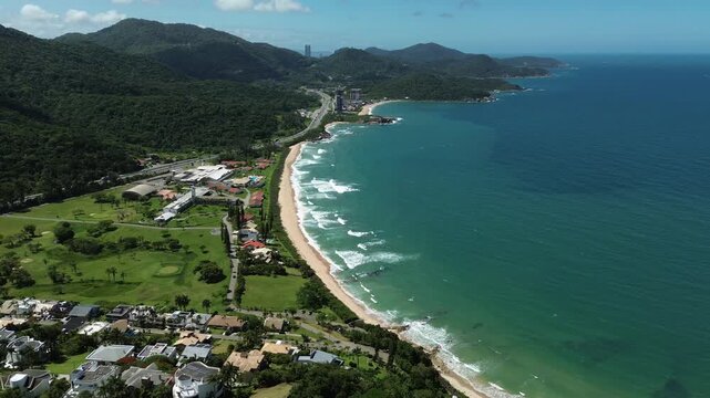 Aerial view of Itapema, Brazil coastline with lush green hills and turquoise waters.