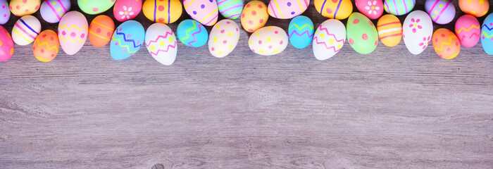 Colorful Easter Egg top border against a wood banner background. Overhead view with copy space. © Jenifoto