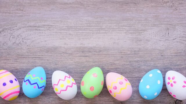 Colorful dancing Easter Egg bottom border on a wood background. Stop motion. Copy space.