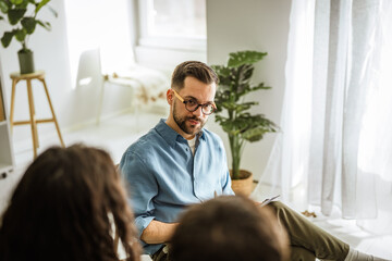 Fototapeta premium Couple discussing relationship problems with a male psychotherapist