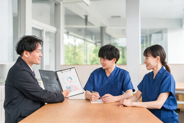 Fototapeta premium Sales, male businessman from a medical equipment manufacturer negotiating with a male medical worker in a scrub