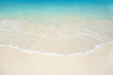 Turquoise ocean wave on clean sandy beach