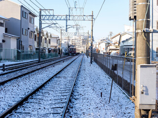 雪が積もる住宅街の鉄道路線