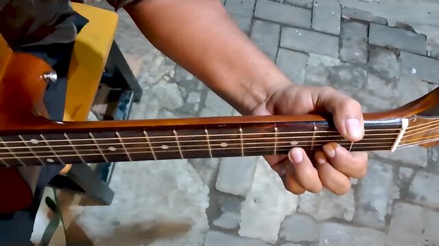 a man's hand playing the guitar at night comfortably