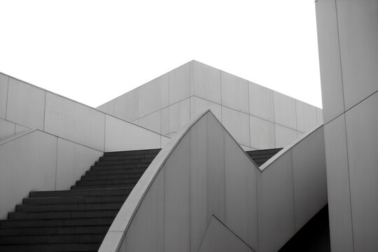 Abstract modern architecture with ascending stairs and intersecting planes, minimalist monochrome design emphasizing geometric shapes and lines.