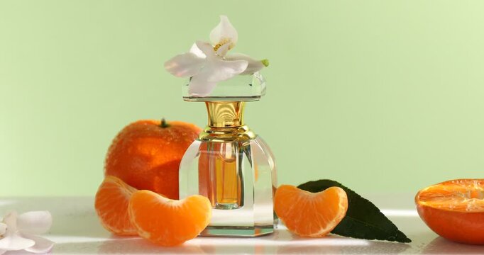 Casting shadow onto bottle of perfume and tangerines on white table, closeup